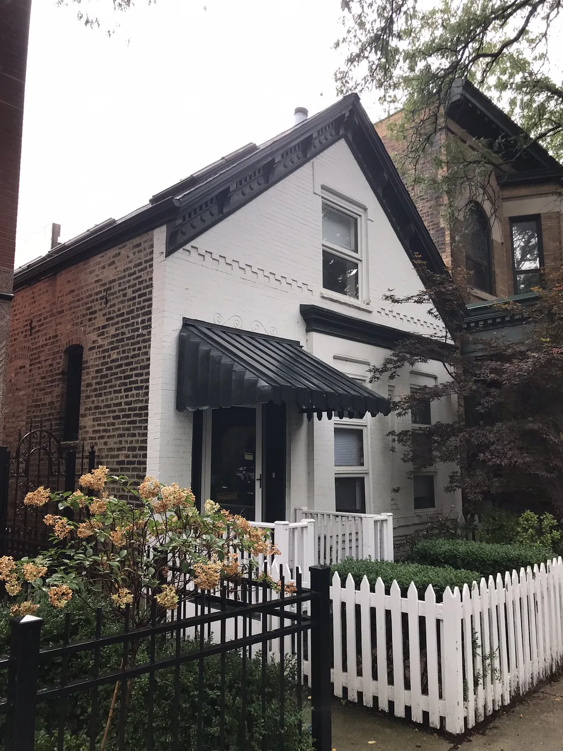 2119 N. Racine Avenue: a gabled cottage, brick below and white clapboard above, behind a white picket fence